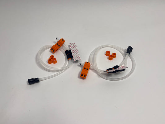 two driver side racing hydration kits showing per set orange dry break fitting holder, 1m silicone tubing connected to it with 3 spacers shown loosely. black silicone bite valve is connected to the tube and velcro positioners connected to the tubing on a light gray background