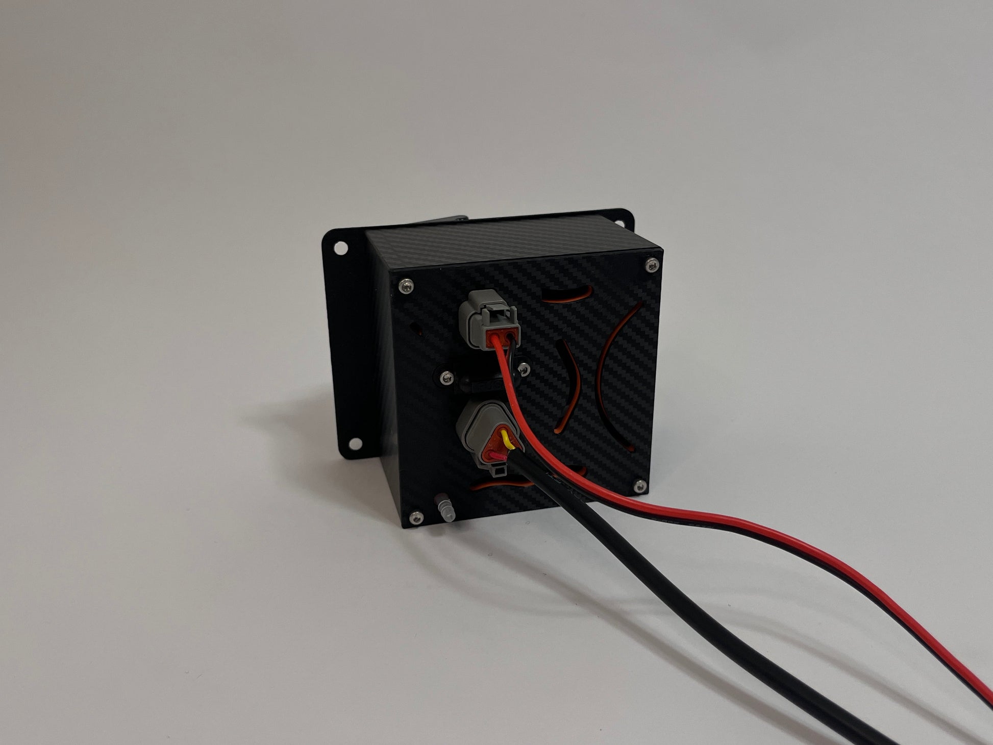 rear of racing hydration unit laying on the side showing a black carbon fiber unit with 2 Deutsch connectors on the rear on a white background
