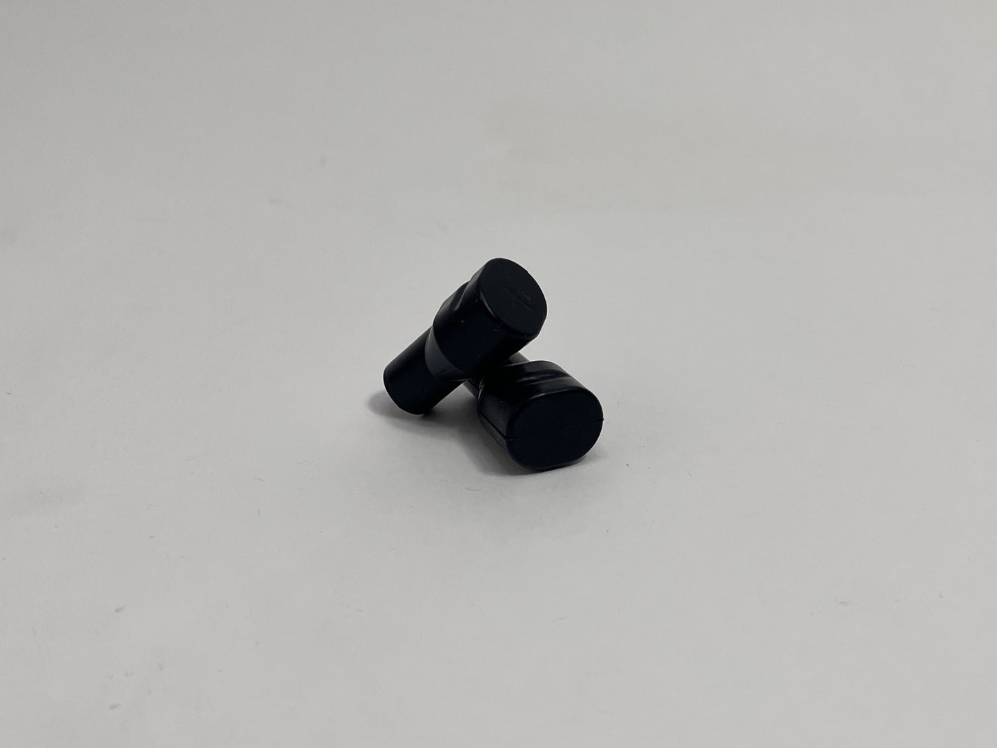 two black silicone bite valves laying against each other, shown on a plain light gray background