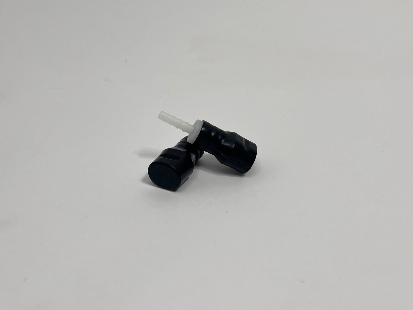 two black silicone bite valves with fittings in it, shown on a plain light gray background