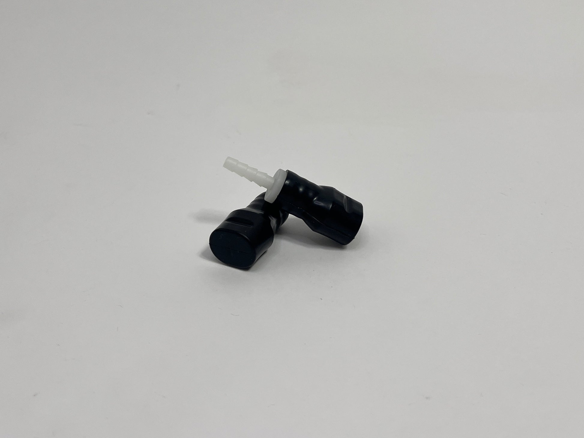 two black silicone bite valves with fittings in it, shown on a plain light gray background