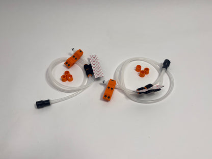 two driver side racing hydration kits showing per set orange dry break fitting holder, 1m silicone tubing connected to it with 3 spacers shown loosely. black silicone bite valve is connected to the tube and velcro positioners connected to the tubing on a light gray background