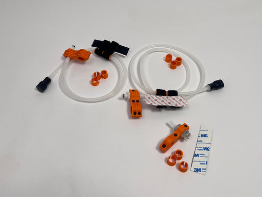 two driver side racing hydration kits showing per set orange dry break fitting holder, 1m silicone tubing connected to it with 3 spacers shown loosely. black silicone bite valve is connected to the tube and velcro positioners connected to the tubing. also a car side connector in orange shown with dry break fitting installed, 3m backed rubber and 3 orange radio plug spacers on a light gray background