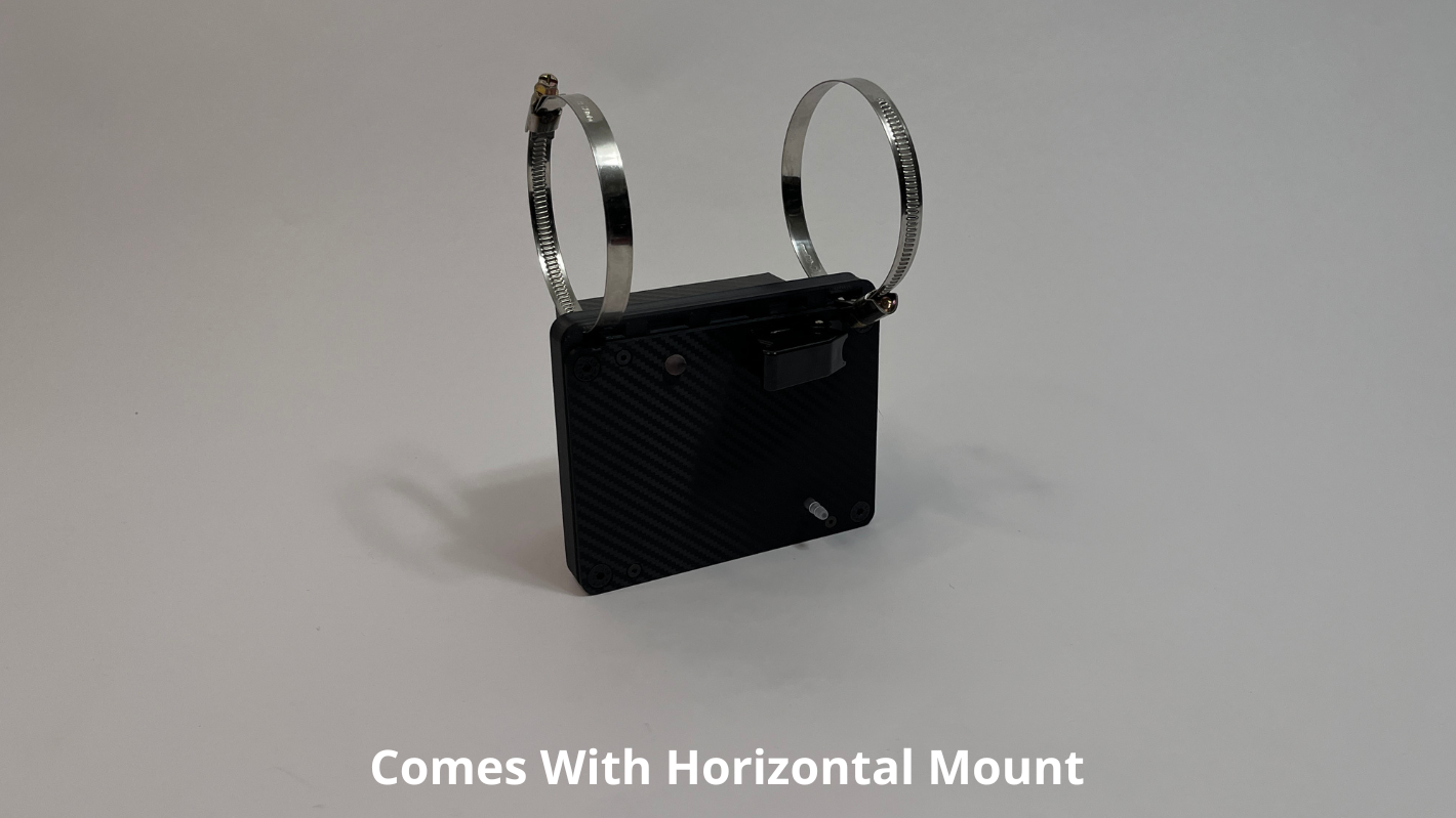 front side of motosport drink pump unit  laying on its side showing a black carbon fiber unit with 2 Deutsch connectors on the rear with 2 roll cage mounts on the top to mount horizontally on a light gray background