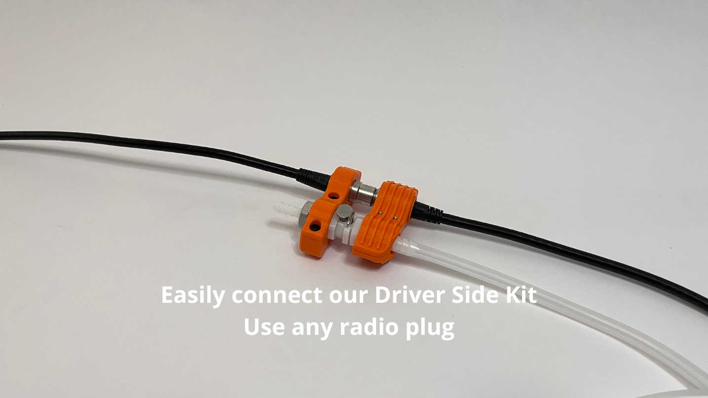 orange car side and driver side motorsport hydration connector holder with radio plug and tubing connected to it on light gray background
