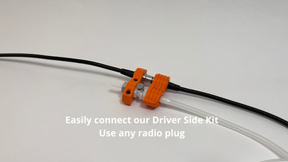 orange car side and driver side motorsport hydration connector holder with radio plug and tubing connected to it on light gray background